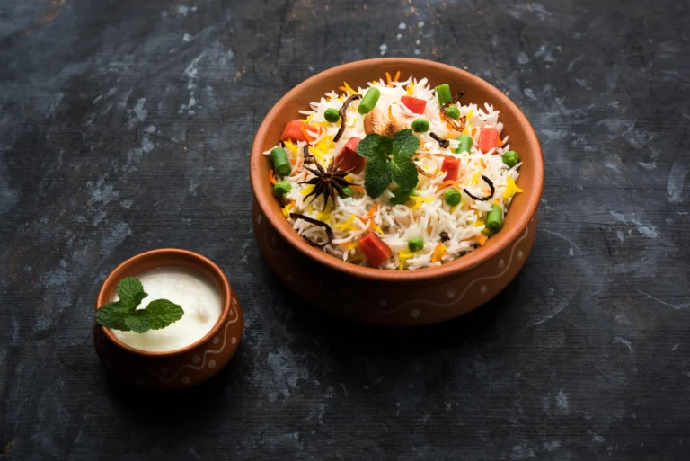 A bowl of colorful long grain basmati rice served with vegetables and raita — showing what is basmati rice and how to cook it perfectly.