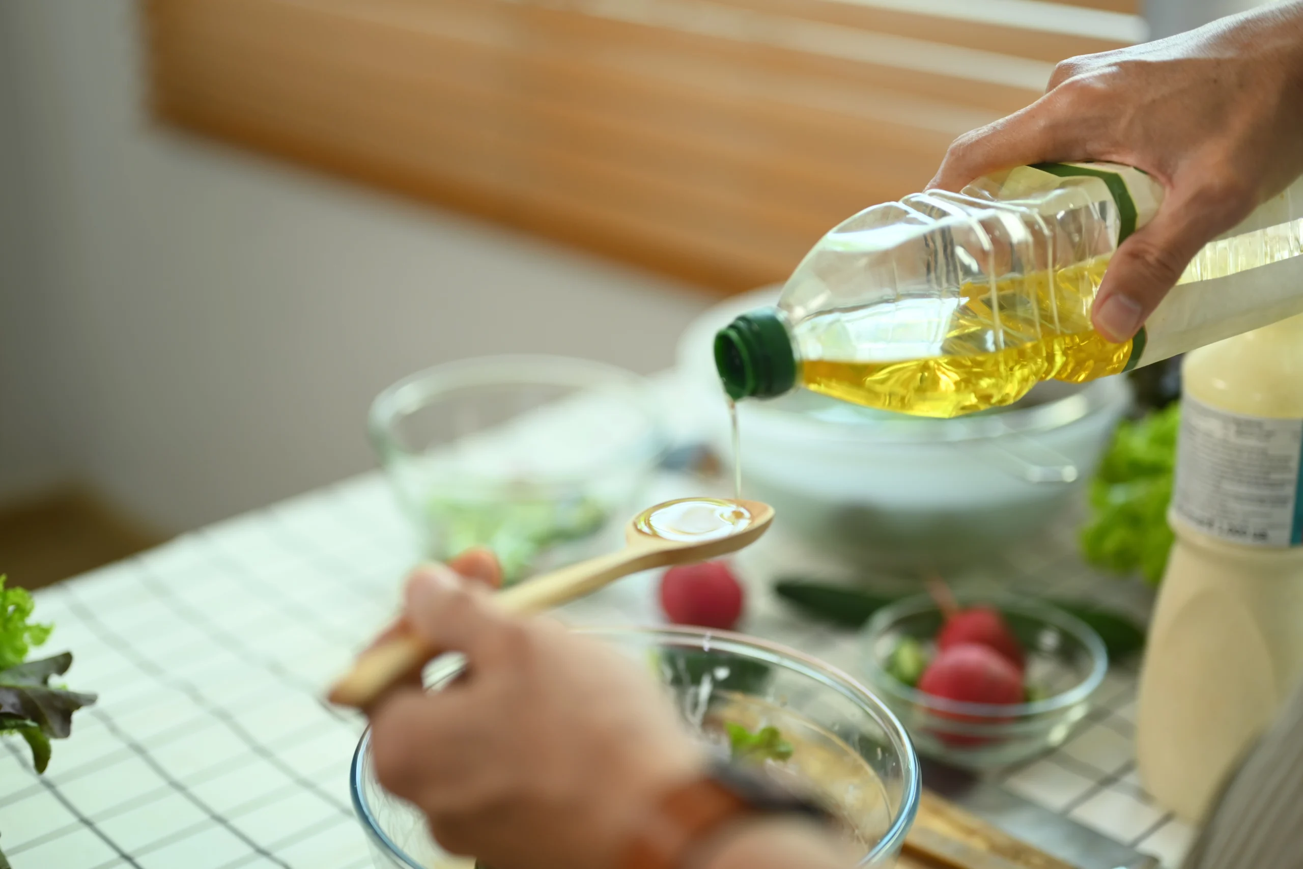 close-up scene of vegetable oil being poured into a wooden spoon during meal preparation, supporting the theme “What Is Vegetable Oil Made Of?”
