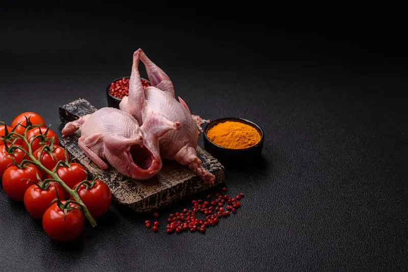 Fresh quails arranged with tomatoes and spices, supporting the broader topic: Is Slim Chickens Halal? and how poultry is sourced and prepared.